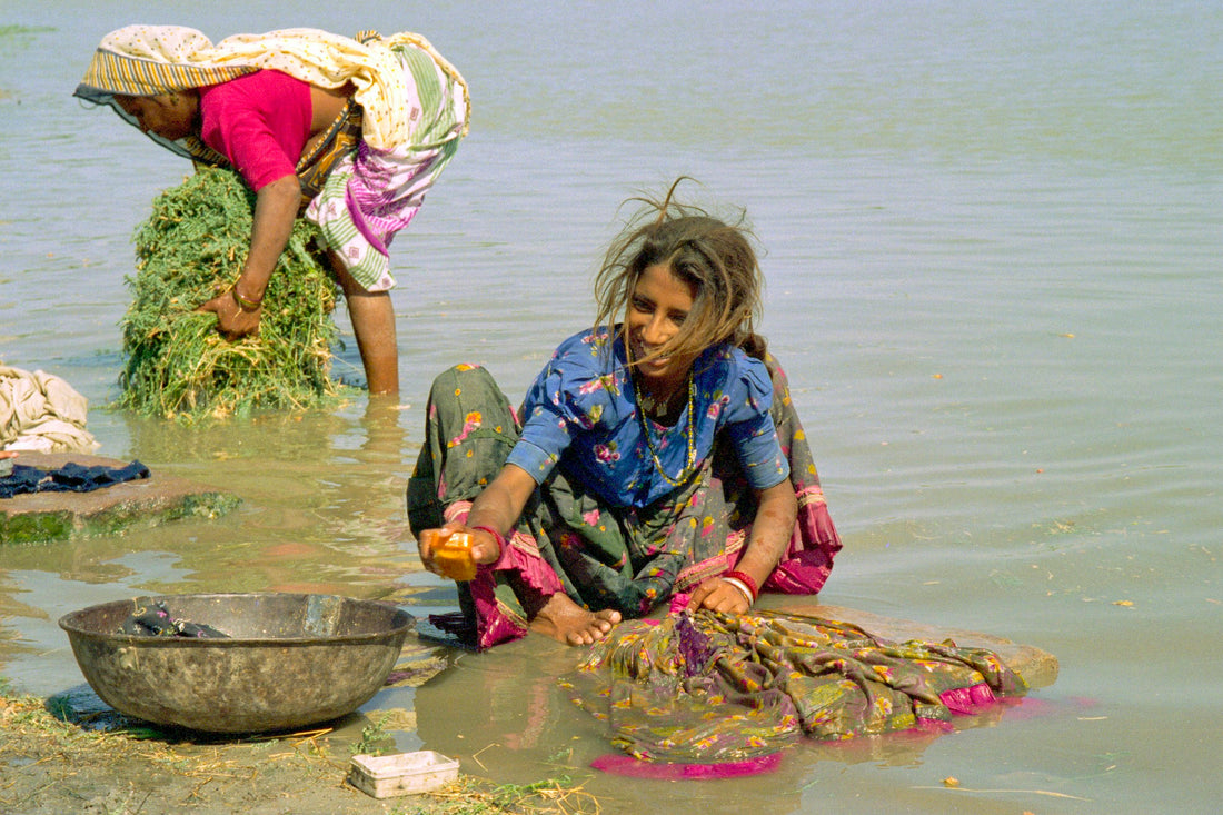 Women washing cloth by hand in a river in Zainabad, Gujarat — the unglamorous finishing work behind hand block printed textiles