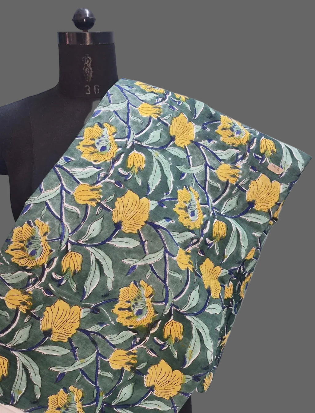 Fabric with yellow floral pattern on a mannequin against a white background