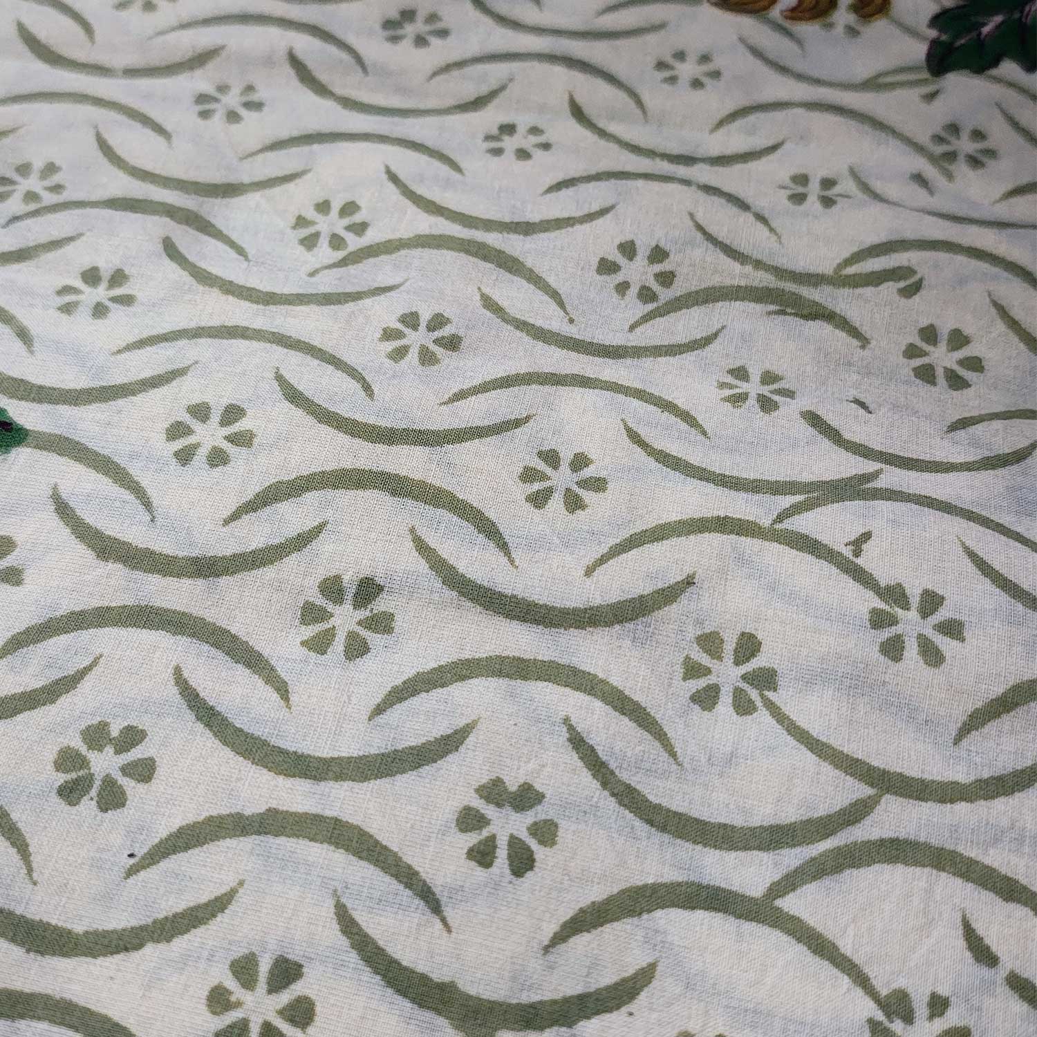 Textile with green floral and wave pattern on a white background
