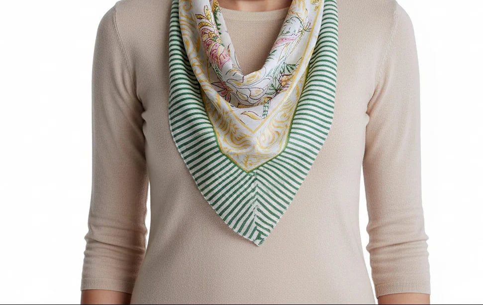 Person wearing a beige long-sleeve shirt with a floral and green striped scarf draped over the shoulder.