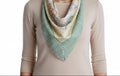 Person wearing a beige long-sleeve shirt with a floral and green striped scarf draped over the shoulder.