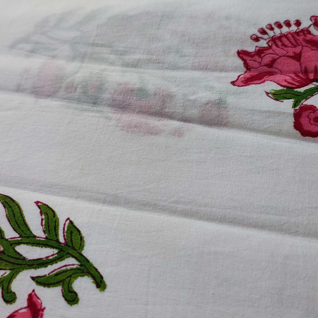 Close-up of embroidered fabric with pink flowers and green leaves on a white background