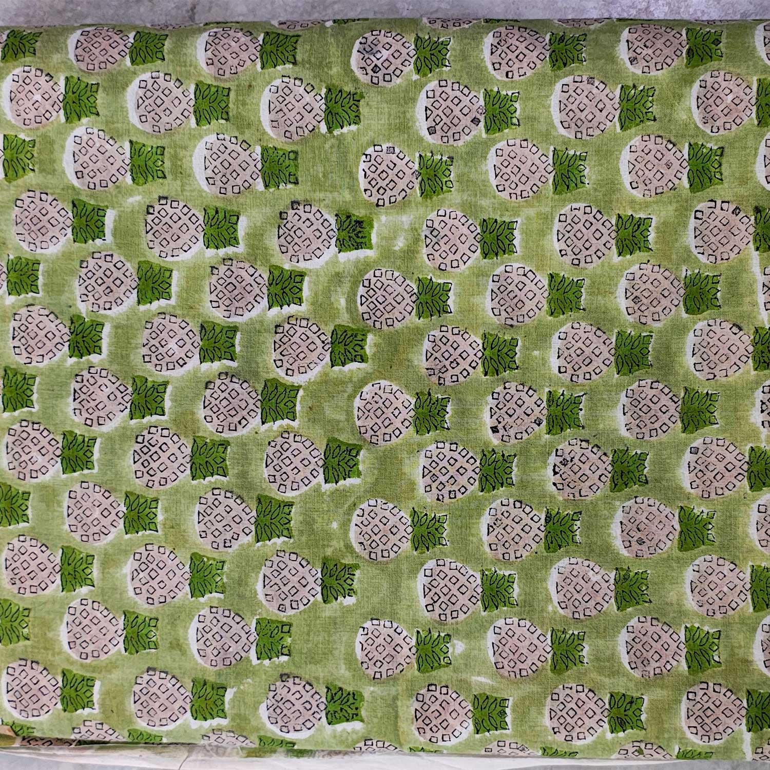 Patterned fabric with green and beige design on a flat surface