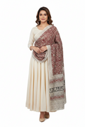 Woman wearing a cream saree with a red and white patterned shawl on a white background