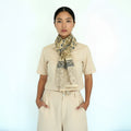 Woman wearing a black top and patterned scarf against a white background