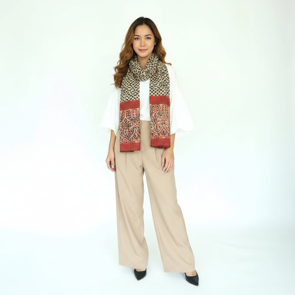 Woman wearing a patterned scarf and beige pants on a white background