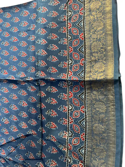Close-up of red buti Ajrakh hand block print and gold zari border on steel blue dola silk
