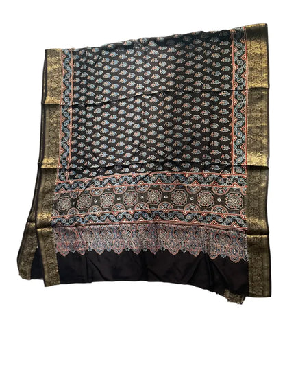 Black hand block printed Ajrakh dupatta laid flat showing rust buti & medallion pallu print, pallu and zari border