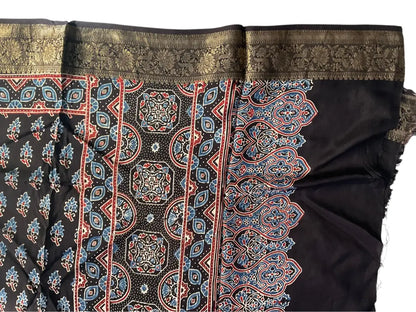 Close-up of rust buti & medallion pallu Ajrakh hand block print and gold zari border on black dola silk