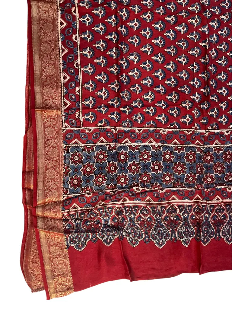 Close-up of indigo floral buti Ajrakh hand block print and gold zari border on maroon red dola silk